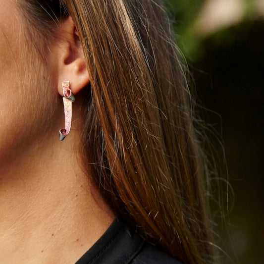 chica luciendo los pendientes de presion largos, color rojizo de la colección bakú de ardentia