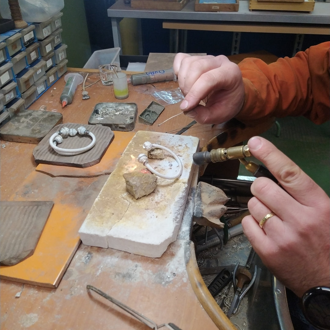 Manuel soldando en nuestro taller el torque de pulsera con azabache